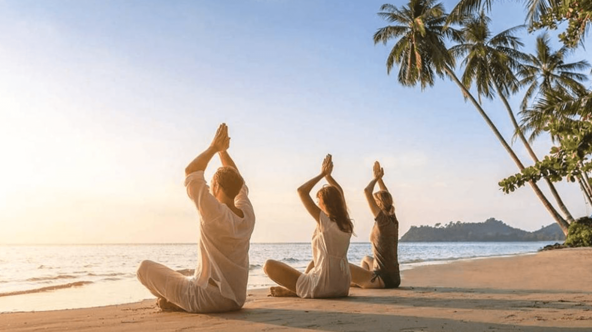 Three people sharing a quiet movement practice beside the sea